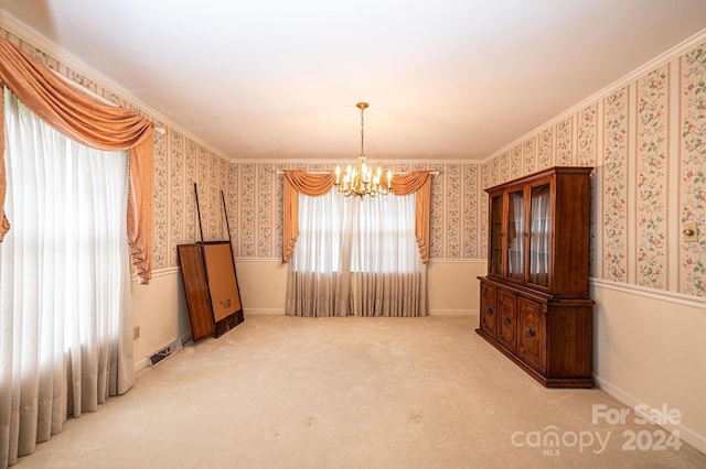 unfurnished room featuring crown molding, a healthy amount of sunlight, light carpet, and an inviting chandelier