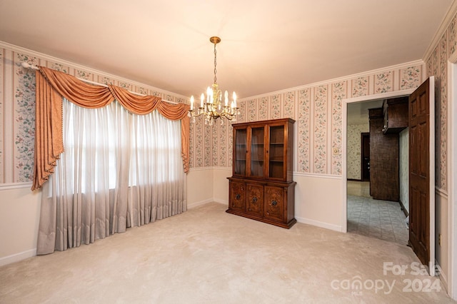 carpeted spare room featuring an inviting chandelier and ornamental molding