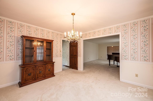 empty room featuring an inviting chandelier, ornamental molding, and carpet floors