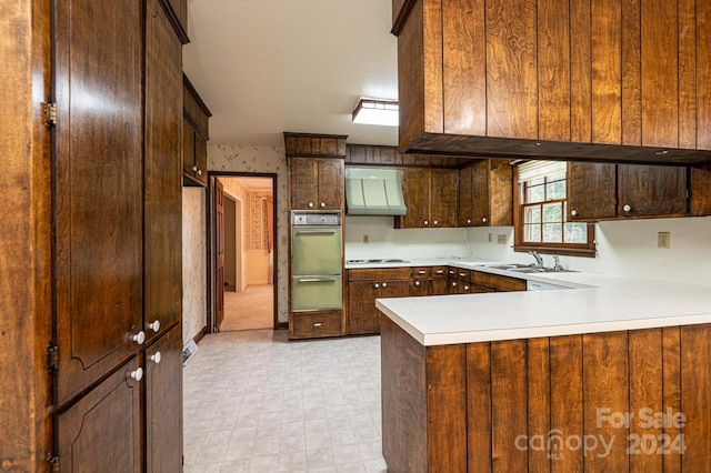 kitchen with sink, white stovetop, kitchen peninsula, oven, and wall chimney exhaust hood