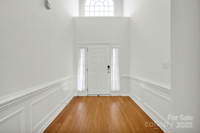 foyer entrance with wood-type flooring and a towering ceiling