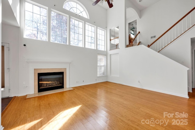 unfurnished living room with hardwood / wood-style flooring, a high ceiling, and ceiling fan