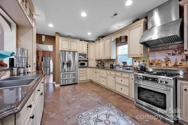 kitchen featuring wall chimney range hood, cream cabinets, and appliances with stainless steel finishes