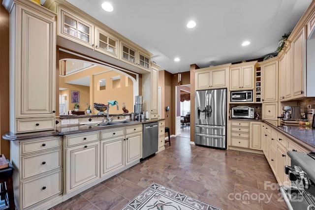 kitchen featuring appliances with stainless steel finishes, sink, decorative backsplash, and cream cabinetry