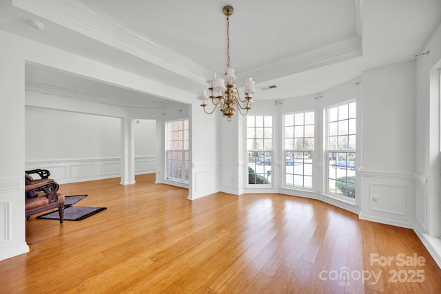 unfurnished dining area with an inviting chandelier, hardwood / wood-style flooring, plenty of natural light, and a raised ceiling