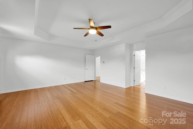 spare room with ornamental molding, a raised ceiling, and light hardwood / wood-style flooring