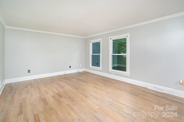 spare room featuring ornamental molding and light hardwood / wood-style floors