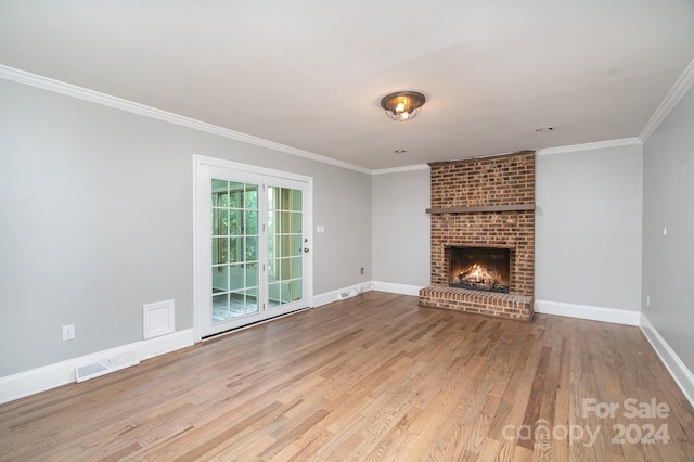 unfurnished living room featuring crown molding, a fireplace, brick wall, and light hardwood / wood-style floors