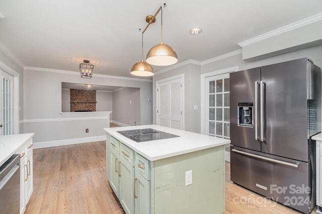 kitchen with appliances with stainless steel finishes, light wood-type flooring, a kitchen island, and decorative light fixtures