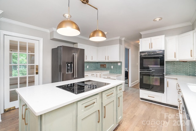 kitchen featuring tasteful backsplash, black appliances, light wood-type flooring, and hanging light fixtures