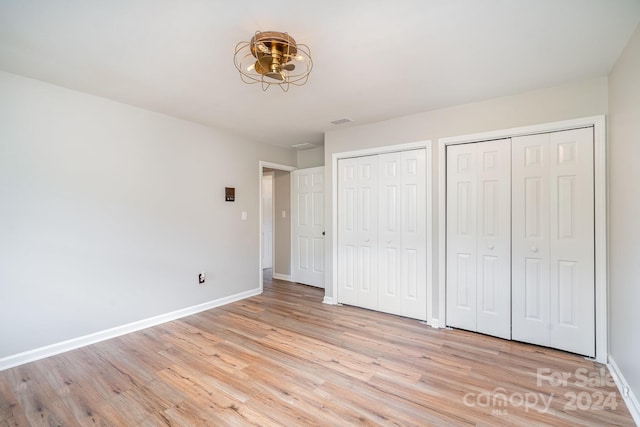 unfurnished bedroom featuring two closets and light hardwood / wood-style floors