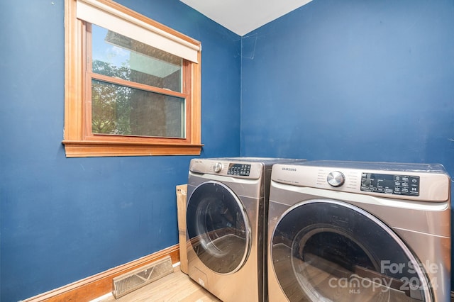 laundry room featuring separate washer and dryer and light hardwood / wood-style floors