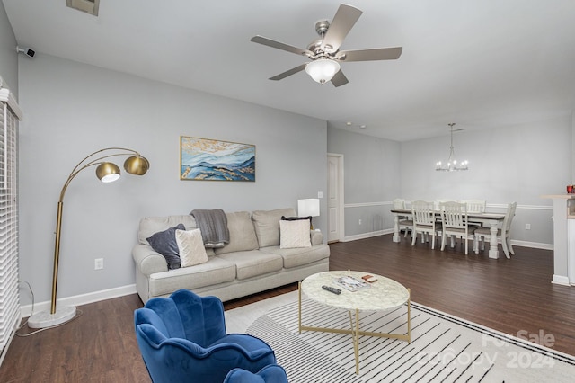 living area with dark wood-type flooring, baseboards, and ceiling fan with notable chandelier