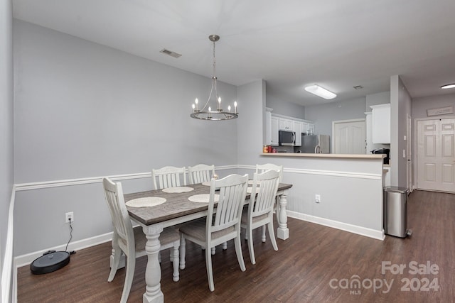 dining space with a chandelier, dark wood-style flooring, visible vents, and baseboards