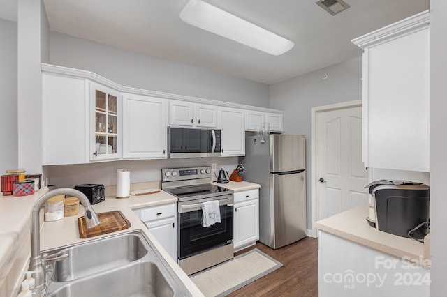 kitchen with glass insert cabinets, appliances with stainless steel finishes, light countertops, and a sink