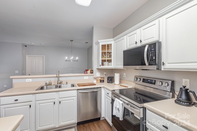 kitchen featuring stainless steel appliances, light countertops, hanging light fixtures, glass insert cabinets, and a sink
