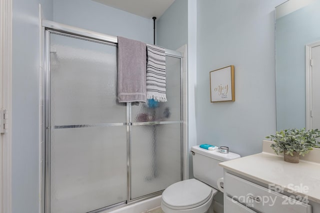 full bath featuring a shower with shower door, vanity, and toilet