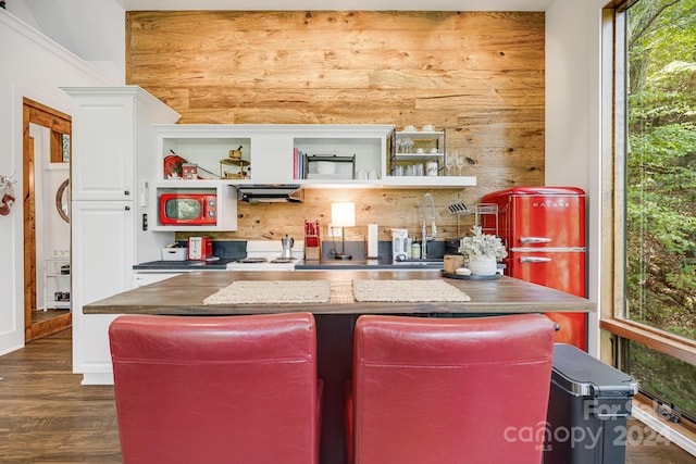 kitchen featuring dark wood-type flooring, white cabinets, a center island, and range hood