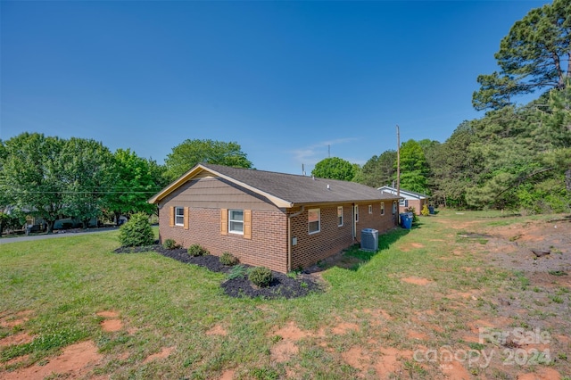 view of side of home with a lawn and central AC