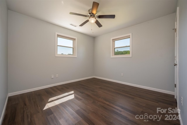 spare room with a wealth of natural light, ceiling fan, and dark hardwood / wood-style floors