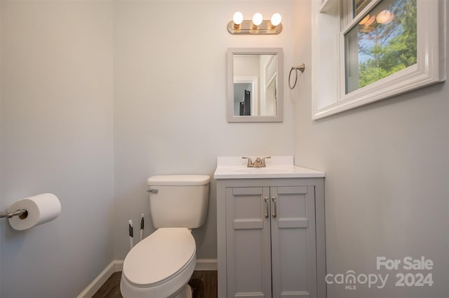 bathroom with hardwood / wood-style flooring, toilet, and vanity