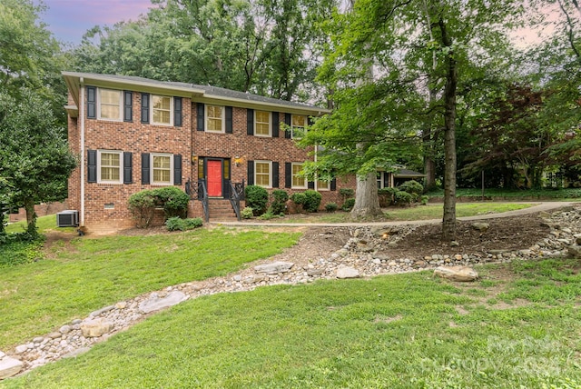 colonial home with a yard and cooling unit