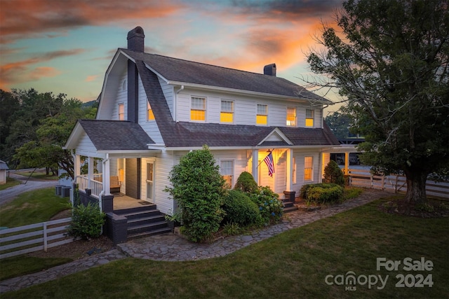 view of front of property with central AC, a yard, and covered porch