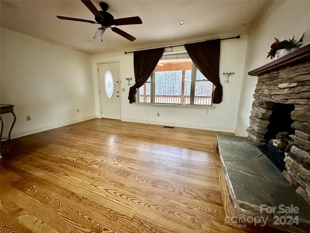 unfurnished living room featuring a fireplace, light hardwood / wood-style flooring, and ceiling fan