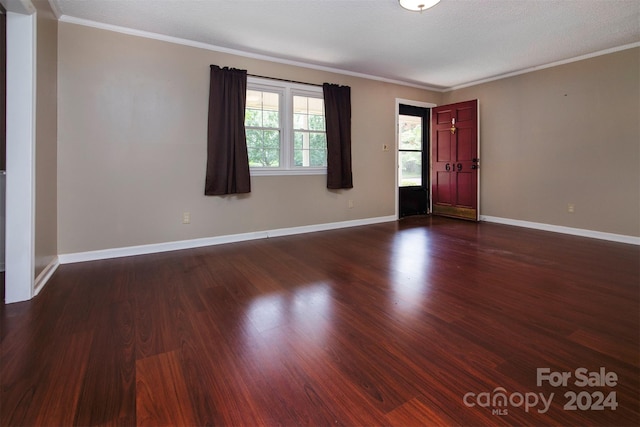 spare room with ornamental molding, a textured ceiling, and dark wood-type flooring