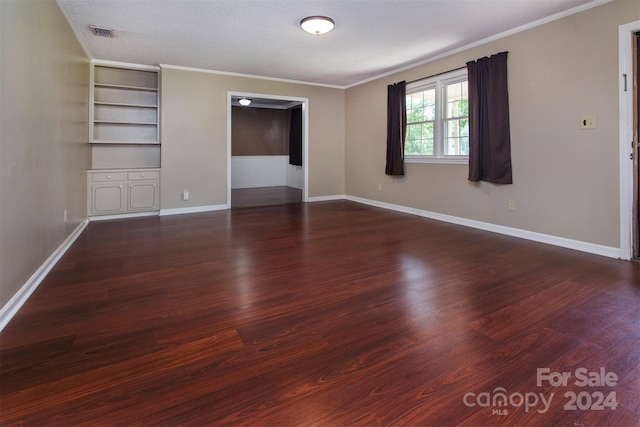 spare room featuring a textured ceiling, visible vents, baseboards, dark wood-style floors, and crown molding