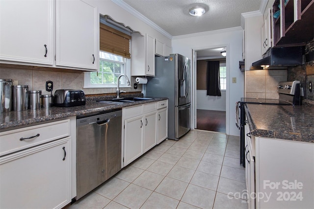 kitchen with light tile patterned floors, stainless steel appliances, a sink, white cabinets, and ornamental molding