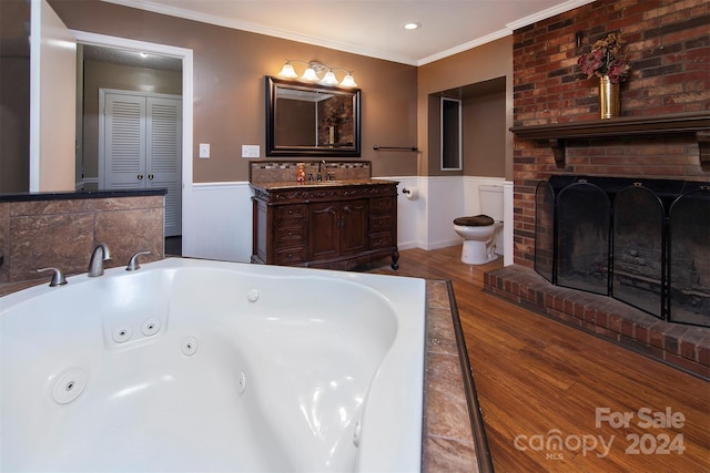 full bathroom with a wainscoted wall, wood finished floors, vanity, ornamental molding, and a jetted tub