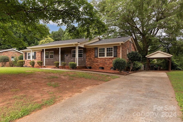 ranch-style home featuring covered porch, driveway, brick siding, and a front lawn