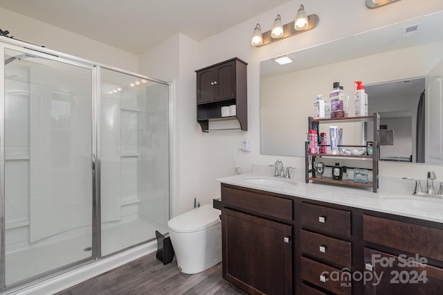 bathroom with toilet, hardwood / wood-style flooring, dual vanity, and an enclosed shower