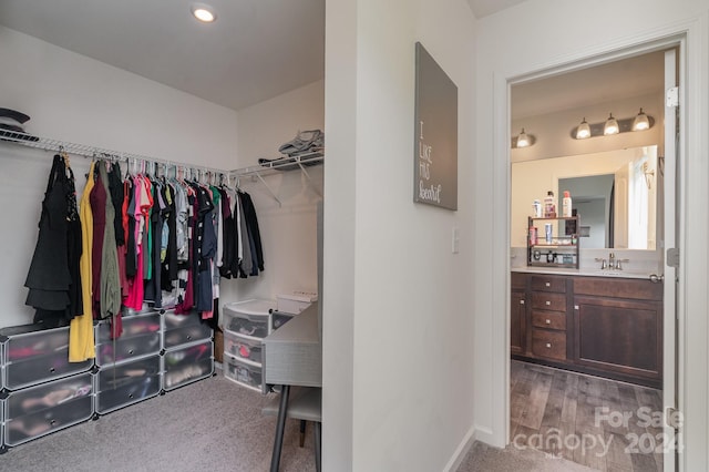 walk in closet with light carpet and sink