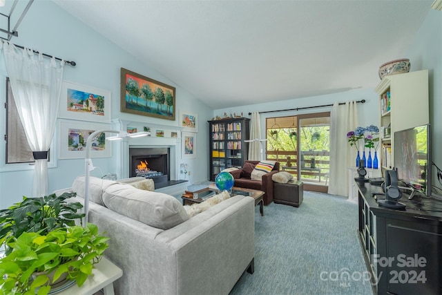 living area featuring lofted ceiling, a lit fireplace, and carpet