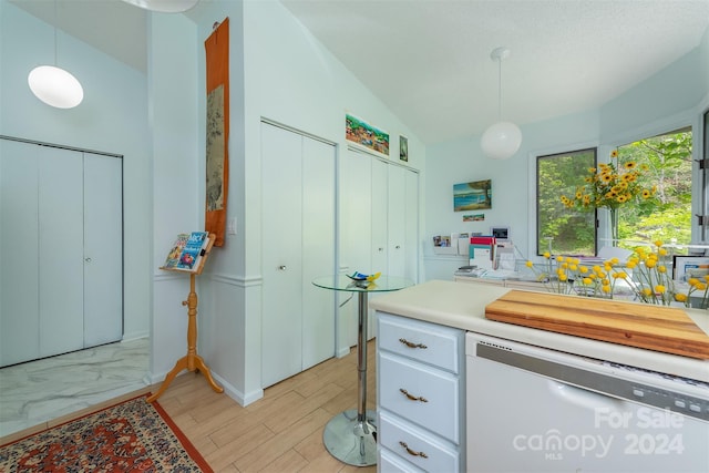 kitchen with light countertops, white dishwasher, white cabinets, and pendant lighting