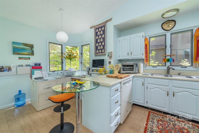 kitchen featuring white cabinets, a peninsula, hanging light fixtures, light countertops, and a sink