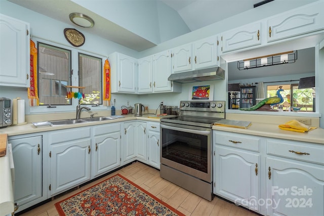 kitchen with under cabinet range hood, electric range, white cabinetry, and light countertops