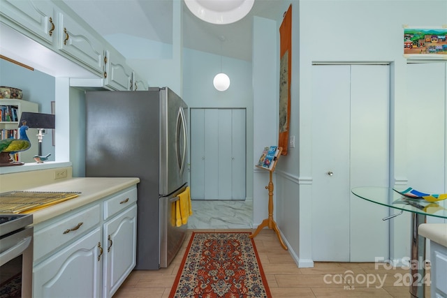 kitchen featuring light wood-style flooring, white cabinets, light countertops, freestanding refrigerator, and decorative light fixtures