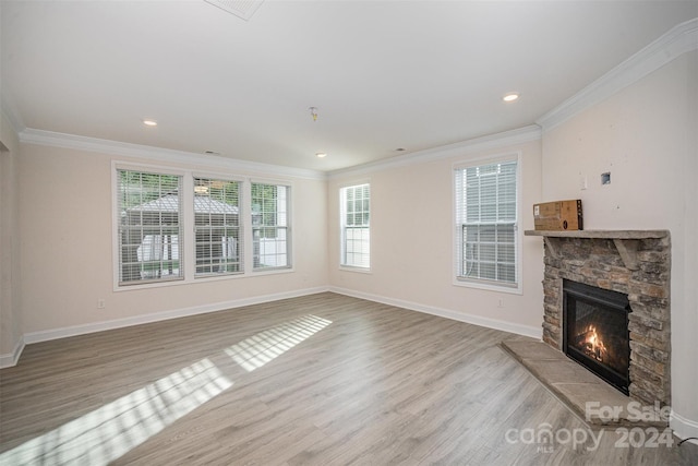 unfurnished living room featuring crown molding, light hardwood / wood-style flooring, and a stone fireplace