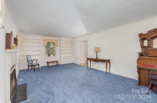 sitting room featuring carpet floors, built in shelves, and ornamental molding