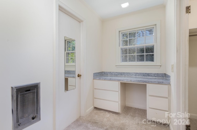 interior space featuring heating unit, light colored carpet, crown molding, and built in desk