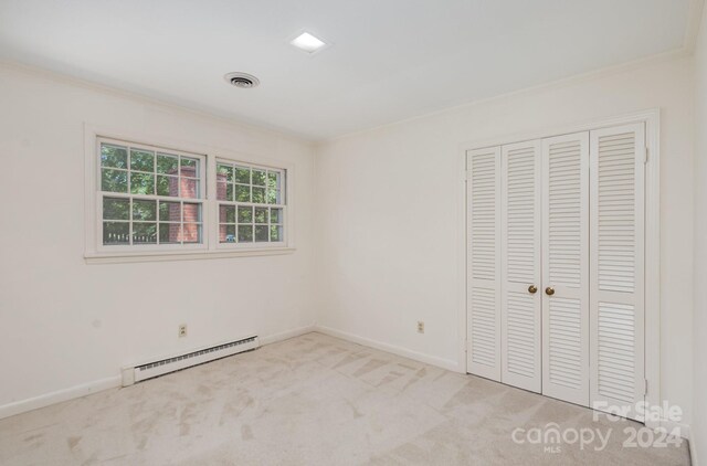 unfurnished bedroom featuring a closet, light carpet, crown molding, and a baseboard radiator