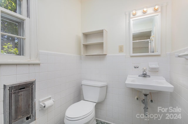 bathroom featuring toilet, plenty of natural light, and tile walls