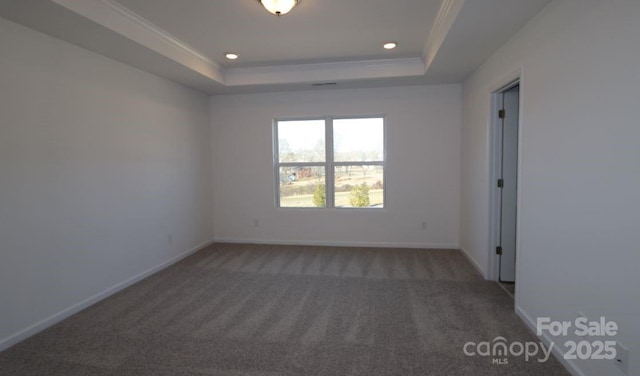 unfurnished room with ornamental molding, a tray ceiling, and dark carpet