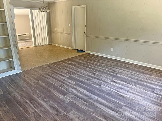 unfurnished room featuring built in shelves, an inviting chandelier, dark hardwood / wood-style floors, and a wall unit AC