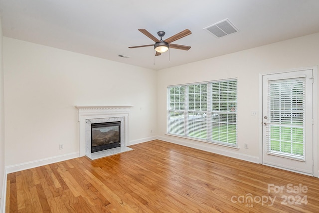 unfurnished living room featuring ceiling fan, light hardwood / wood-style flooring, and a premium fireplace