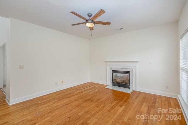 unfurnished living room featuring ceiling fan, a high end fireplace, and light wood-type flooring