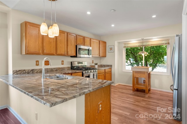 kitchen with light wood finished floors, a peninsula, recessed lighting, a sink, and stainless steel appliances